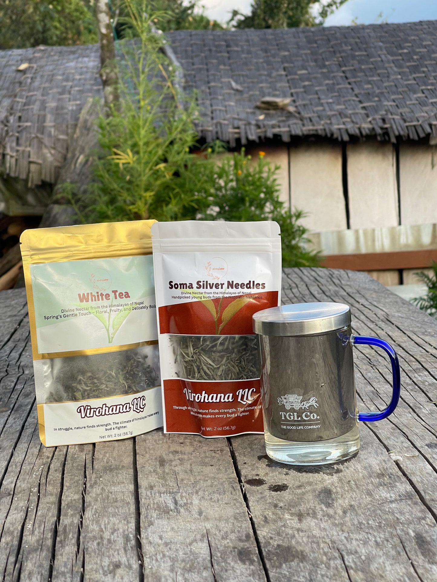 Soma silver and white tea packages and a mug on a wooden table outdoors.