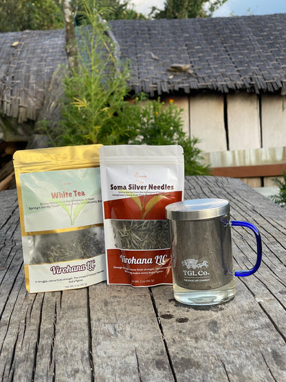 Soma silver and white  tea packages and a mug on a wooden table outdoors.