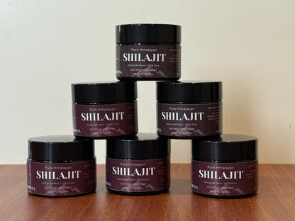 Stack of Shilajit containers on a wooden surface with a neutral background