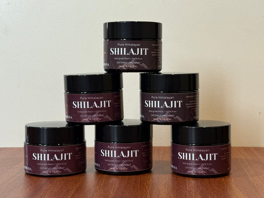 Stack of Shilajit containers on a wooden surface with a neutral background