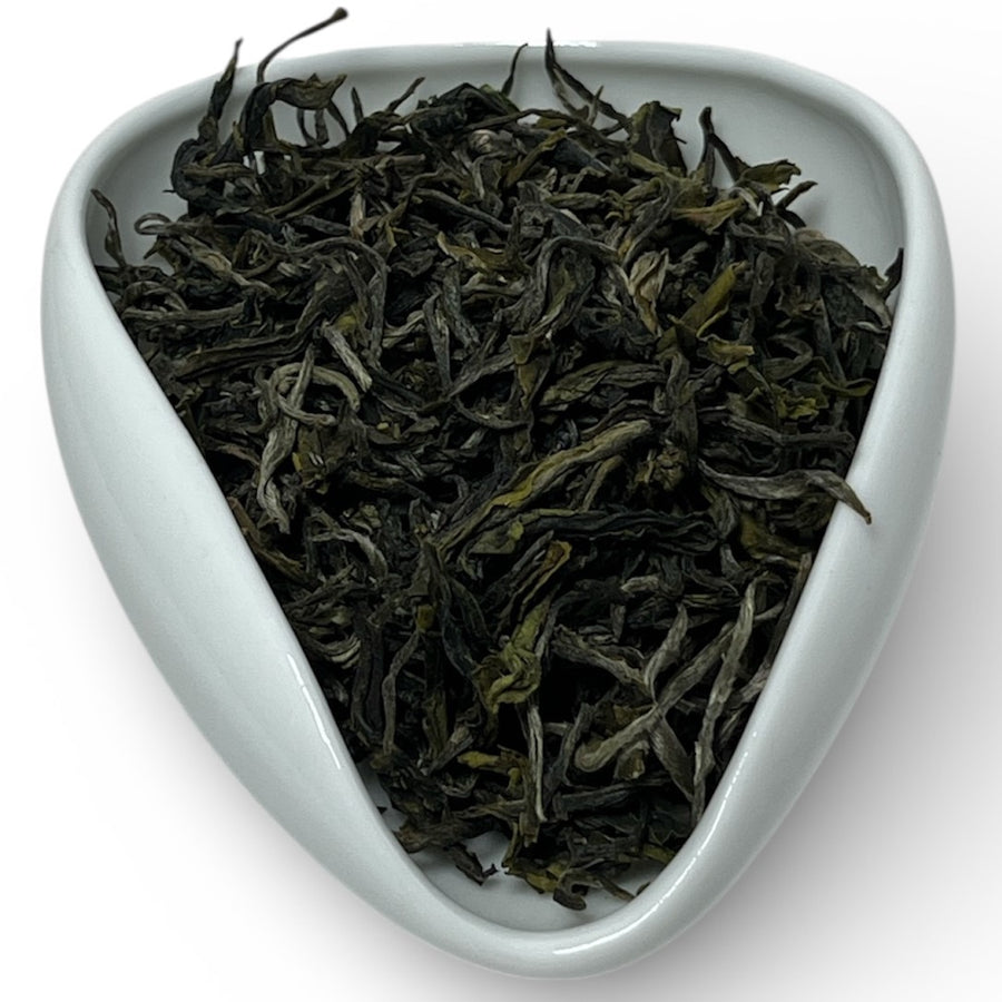 Tea leaves in a white triangular dish on a white background