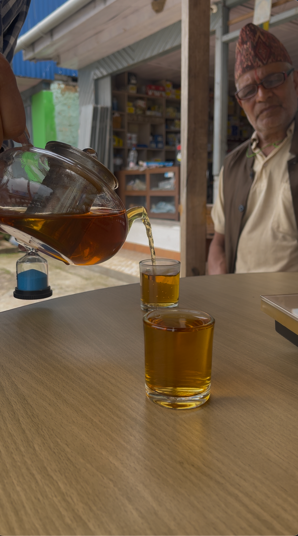 roasted green tea pouring from a kettle to a cup with a local village man on the side
