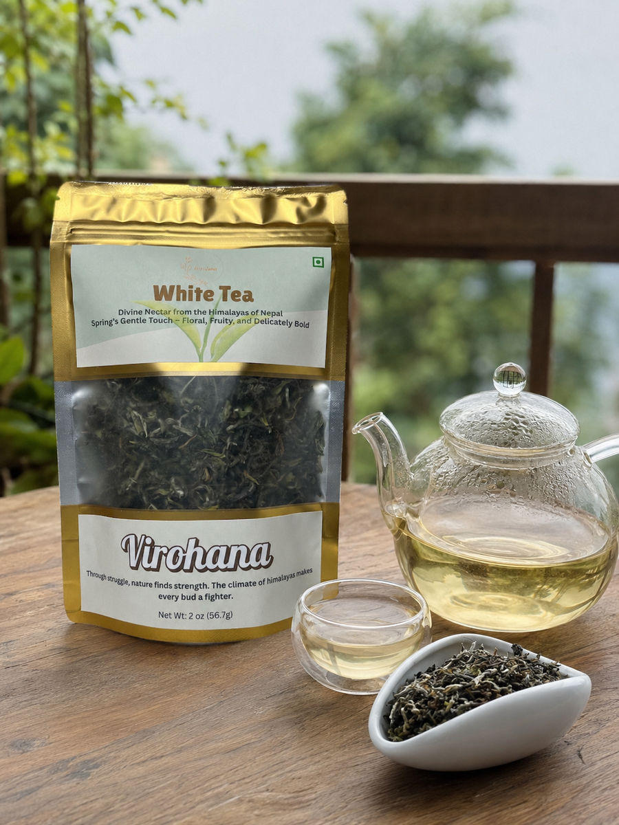 White tea package with a teapot, cup, and loose tea on a wooden table.
